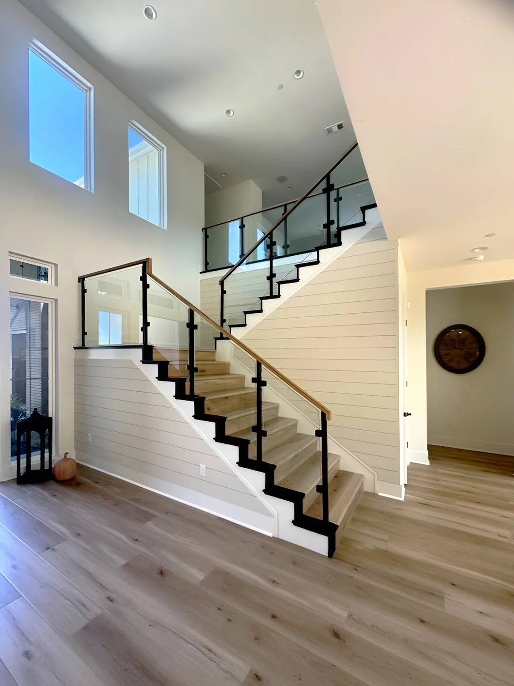 Glass Railings - Murrieta CA Glass railings with black iron posts and wood handrail on staircase with landing in Murrieta, California home